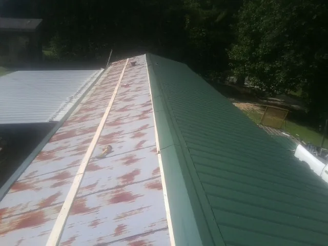 Old rusted panels beside newly installed green metal roofing — Wind Damage Roof Repair by Roofing Brothers in Chilhowee