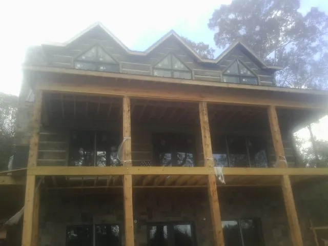 Dormers and porch framing on a large log home under construction — Roof Coating work by our crew in Chilhowee