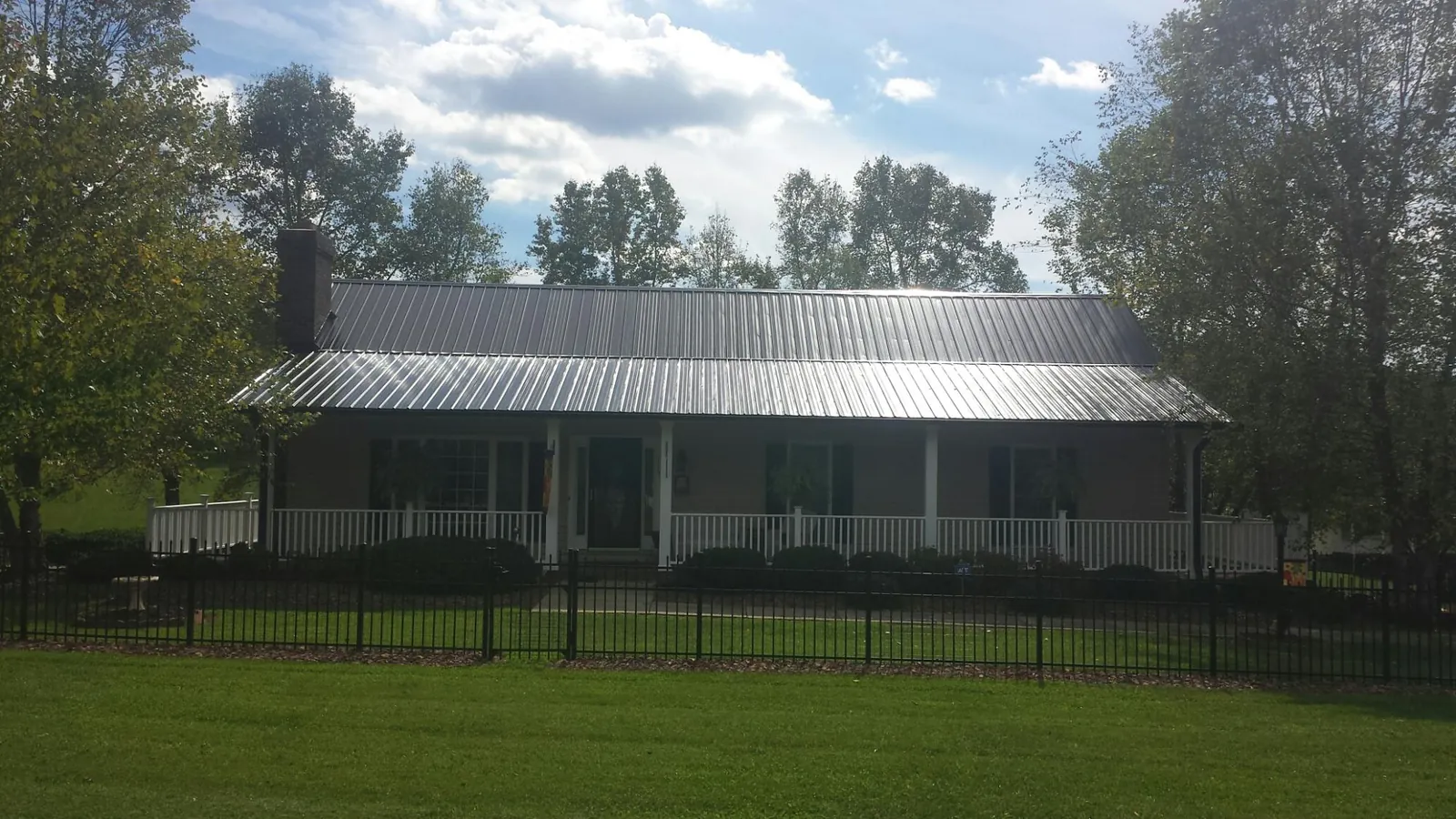 Gray metal roof on a brick ranch with a full width front porch — Gutter Guard Installation work by our crew in Chilhowee